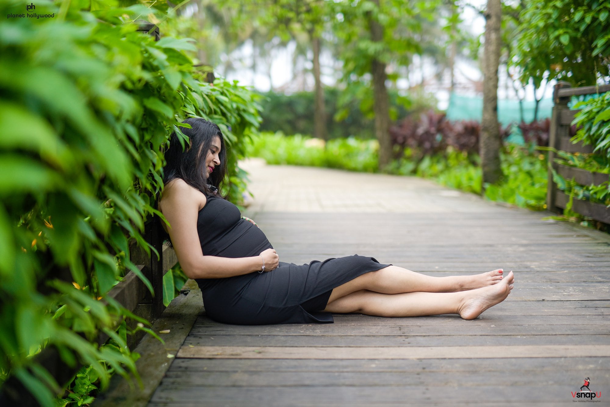 Nature’s warmth surrounds an expecting mother as she lies in a sunset-lit garden.